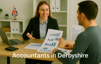A professional accountant in a modern Derbyshire office explains financial charts to a client across a tidy desk with a laptop, spreadsheets, and calculators. A small British flag and HMRC document in the background suggest a UK business setting. Overlay text reads Accountants in Derbyshire