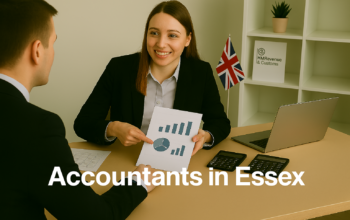 A professional accountant in a modern Essex office explains financial charts to a client across a tidy desk with a laptop, spreadsheets, and calculators. A small British flag and HMRC document in the background suggest a UK business setting. Overlay text reads Accountants in Essex