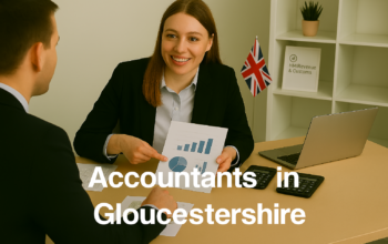 A professional accountant in a modern Gloucestershire office explains financial charts to a client across a tidy desk with a laptop, spreadsheets, and calculators. A small British flag and HMRC document in the background suggest a UK business setting. Overlay text reads Accountants in Gloucestershire