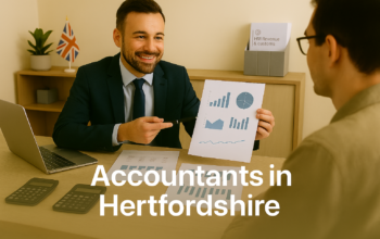A professional accountant in a modern Hertfordshire office explains financial charts to a client across a tidy desk with a laptop, spreadsheets, and calculators. A small British flag and HMRC document in the background suggest a UK business setting. Overlay text reads Accountants in Hertfordshire