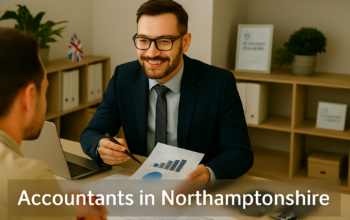 A professional accountant in a modern Northamptonshire office explains financial charts to a client across a tidy desk with a laptop, spreadsheets, and calculators. A small British flag and HMRC document in the background suggest a UK business setting. Overlay text reads Accountants in Northamptonshire