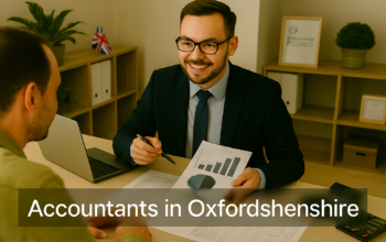 A professional accountant in a modern Oxfordshire office explains financial charts to a client across a tidy desk with a laptop, spreadsheets, and calculators. A small British flag and HMRC document in the background suggest a UK business setting. Overlay text reads Accountants in Oxfordshire