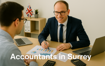 A professional accountant in a modern Surrey office explains financial charts to a client across a tidy desk with a laptop, spreadsheets, and calculators. A small British flag and HMRC document in the background suggest a UK business setting. Overlay text reads Accountants in Surrey