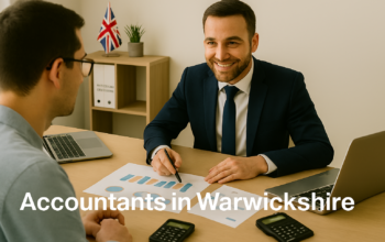 A professional accountant in a modern Warwickshire office explains financial charts to a client across a tidy desk with a laptop, spreadsheets, and calculators. A small British flag and HMRC document in the background suggest a UK business setting. Overlay text reads Accountants in Warwickshire