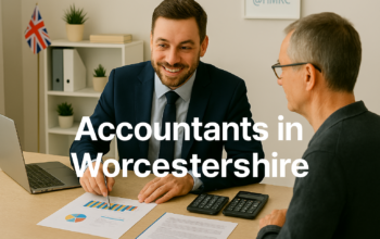 A professional accountant in a modern Worcestershire office explains financial charts to a client across a tidy desk with a laptop, spreadsheets, and calculators. A small British flag and HMRC document in the background suggest a UK business setting. Overlay text reads Accountants in Worcestershire